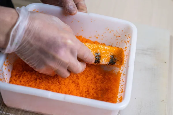 Cook hands making japanese sushi roll. Japanese chef at work preparing delicious sushi roll with eel and avocado. Appetizing japanese food.