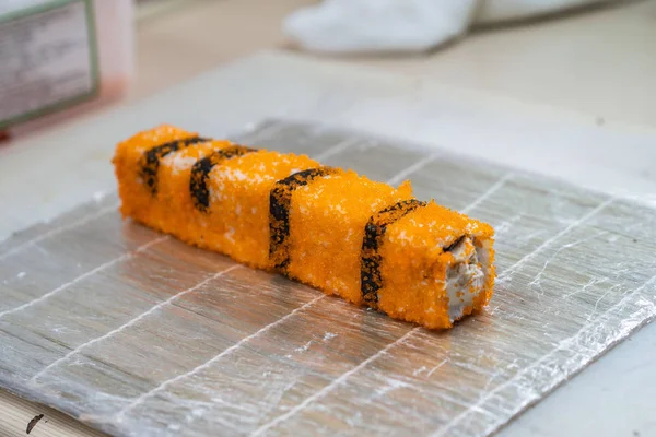 Μαγείρεψε χέρια που φτιάχνουν γιαπωνέζικο ρολό σούσι. Ιαπωνικά σεφ στην εργασία προετοιμασία νόστιμα ρολό σούσι με χέλι και αβοκάντο. Ορεκτικό γιαπωνέζικο φαγητό. — Φωτογραφία Αρχείου