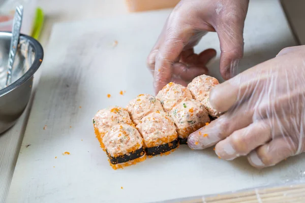 Cook hands making japanese sushi roll. Japanese chef at work preparing delicious sushi roll with eel and avocado. Appetizing japanese food. — Stock Photo, Image