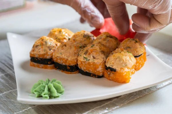 A szakácsok japán sushi tekercset készítenek. A japán séf finom sushi tekercset készít angolnával és avokádóval. Étvágygerjesztő japán étel. — Stock Fotó