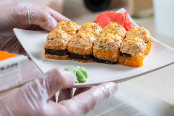 Cocinar las manos haciendo rollo de sushi japonés. Chef japonés en el trabajo preparando delicioso rollo de sushi con anguila y aguacate. Apetitivo comida japonesa. — Foto de Stock