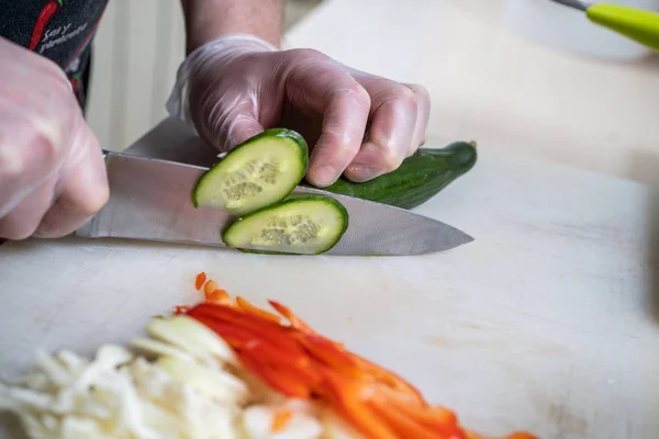 Chef cuts the vegetables into a meal. Preparing dishes. A man uses a knife and cooks.