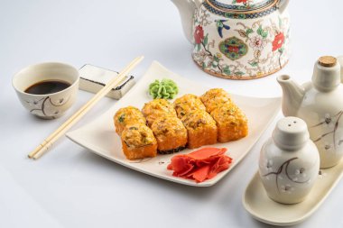 Altın kenarlıklı beyaz plaka üzerinde pişmiş rulo tarak, baharatlı sosu, krem peynir ve pirinç ile mango. Asya menü