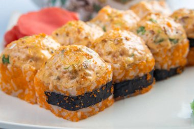 Altın kenarlıklı beyaz plaka üzerinde pişmiş rulo tarak, baharatlı sosu, krem peynir ve pirinç ile mango. Asya menü