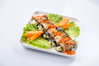 Patlıcan ile fındık beyaz bir plaka üzerinde rulo.