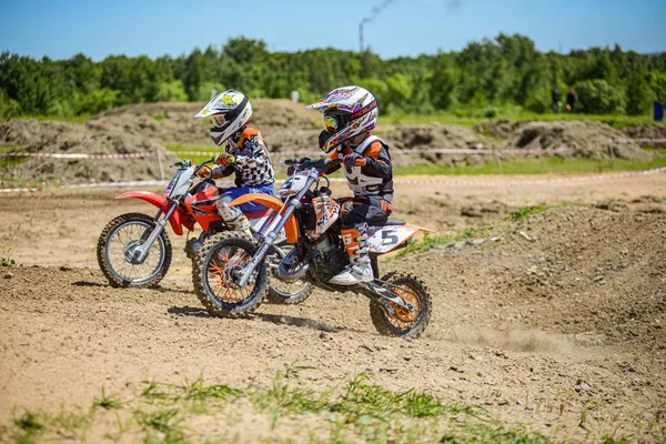 KHABAROVSK, RÚSSIA - 16 de junho de 2019: Criança piloto em motocicleta participa de motocross-country em voo, pula e decola no trampolim contra o céu. Conceito ativo extremo resto adolescente . — Fotografia de Stock