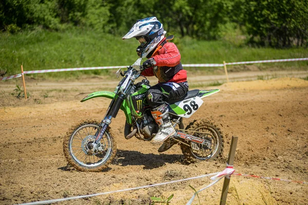 KHABAROVSK, RUSIA - 16 de junio de 2019: Niño corredor en motocicleta participa en motocross cross-country en vuelo, salta y despega en trampolín contra el cielo. Concepto activo descanso extremo adolescente . — Foto de Stock