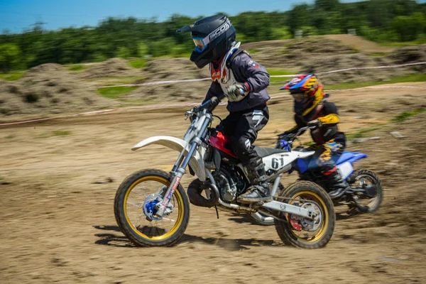 KHABAROVSK, RUSIA - 16 de junio de 2019: Niño corredor en motocicleta participa en motocross cross-country en vuelo, salta y despega en trampolín contra el cielo. Concepto activo descanso extremo adolescente . — Foto de Stock