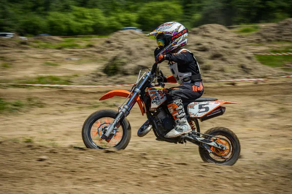 KHABAROVSK, RUSIA - 16 de junio de 2019: Niño corredor en motocicleta participa en motocross cross-country en vuelo, salta y despega en trampolín contra el cielo. Concepto activo descanso extremo adolescente . —  Fotos de Stock