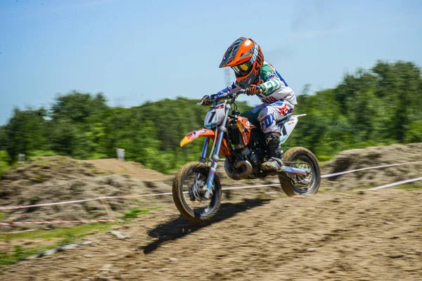 KHABAROVSK, RUSIA - 16 de junio de 2019: Niño corredor en motocicleta participa en motocross cross-country en vuelo, salta y despega en trampolín contra el cielo. Concepto activo descanso extremo adolescente . — Foto de Stock