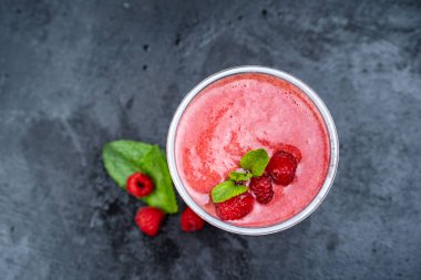 Saman, üç ahududu ve nane yaprakları ile dekore edilmiş bir ahşap panoları, bir ahududu Smoothie cam üst görünümü. Seçici odak