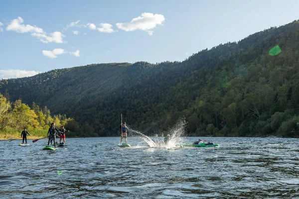 KHABAROVSK, RUSIA - 20 de septiembre de 2019: Los turistas acuáticos remo SUP Stand up paddle board on the mountain river Anyui against the background of beautiful mountains and wildlife —  Fotos de Stock
