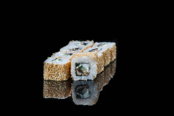 Sushi tekercs egy fekete háttér elmélkedés. Japán kaja. Közelkép. — Stock Fotó