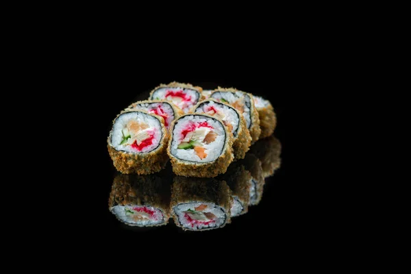 Un primo piano di cibo fritti rotoli di sushi isolati su nero. riflessione — Foto Stock