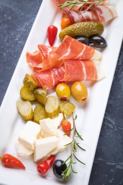 Salatalık turşusu ve pişirilmiş et silindirleriyle servis edilen zeytinler.