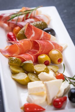 Salatalık turşusu ve pişirilmiş et silindirleriyle servis edilen zeytinler.