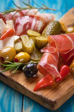 Salatalık turşusu ve pişirilmiş et silindirleriyle servis edilen zeytinler.