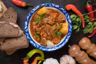 Yuvarlak kâsede Macar kebabı, domuz eti veya sığır eti yahnisi servis edilir.