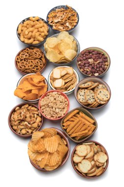 Simitler, patates cipsleri, krakerler ve beyaz arka planda izole edilmiş diğer tuzlu atıştırmalıklar.
