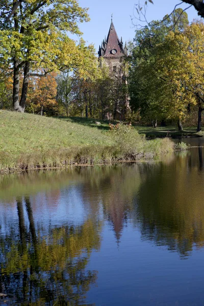 秋天的树与明亮的叶子反映在湖和古代建筑的废墟 — 图库照片
