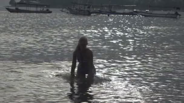 La silueta de la joven esbelta mujer feliz que se para en el mar y salpica las manos de agua.cámara lenta — Vídeos de Stock