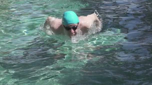 Il giovane sportivo galleggia in piscina una farfalla al seno sulla macchina fotografica, rallentatore — Video Stock