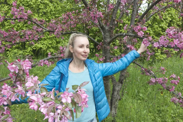 若い魅力的な女性クリムゾン開花近く立っているリンゴの木 — ストック写真