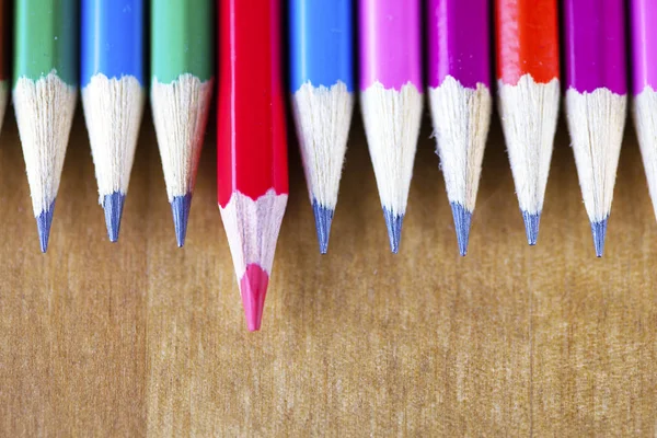 black lead pencils lie in a row, one pencil has a red core and put forward