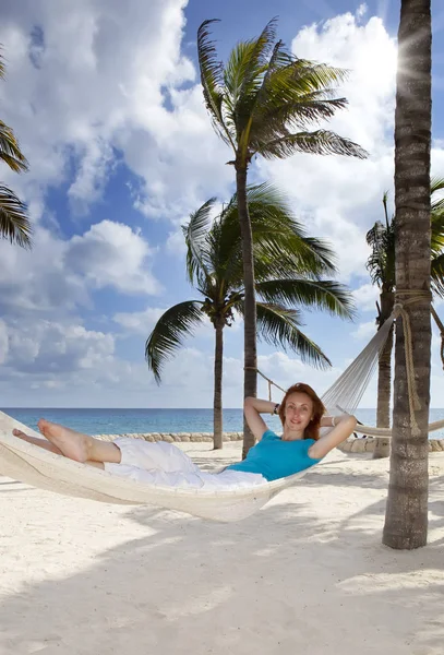 美丽的年轻女子在海滩上的棕榈树和大海的背景吊床 — 图库照片