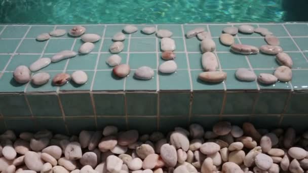 Celebración del año nuevo, la Fecha 2019 está dispuesta por piedras de guijarro en el borde de la piscina en el complejo tropical — Vídeos de Stock