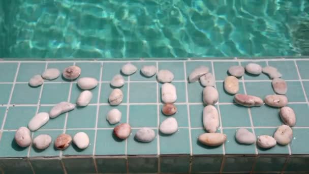 Celebration of new year,Date 2019 is laid out by pebble stones on the edge of the pool in the tropical resort — Stock Video