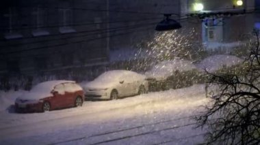 Şehirde bir sokak lambası ile şehrin gece kar yağışı karla kaplı otomobillerde yaktı