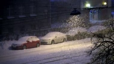 Şehirde bir sokak lambası ile şehrin gece kar yağışı karla kaplı otomobillerde yaktı