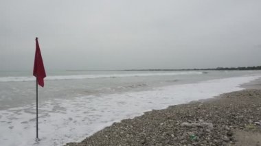 The panorama of the Bali Jimbaran Indonesia beach, Red flag a signal of the ban to bathe because of a big wave, surfers ride boards on a wave