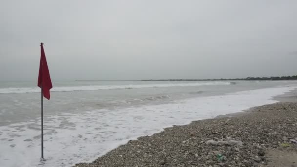 O panorama da praia de Bali Jimbaran Indonésia, bandeira vermelha um sinal da proibição de tomar banho por causa de uma grande onda, surfistas montam pranchas em uma onda — Vídeo de Stock