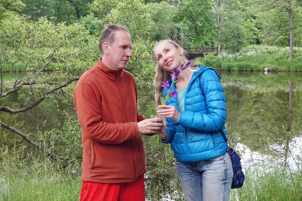约会的男人在夏天在湖上的公园里给女人一朵钟花 — 图库照片