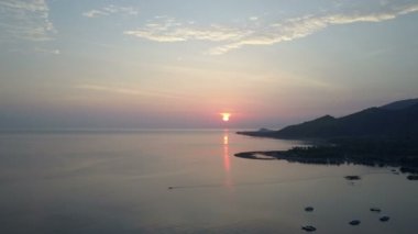 Pemuteran, Drone havadan görünümü, Taşlı deniz kıyısı ve gün batımında dağlar. Endonezya. Bali