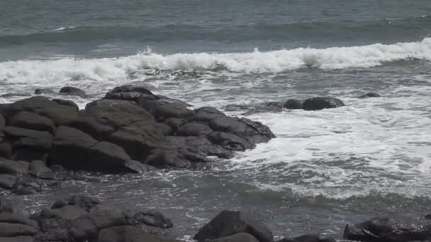 在阳光明媚的日子里 热带海洋的海岸 波浪带着黑色的石头在海岸上奔流 缓慢地运动着 — 图库视频影像