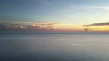 Tropik denizde gün doğumu. Drone'dan aero çekimi, palmiye ağaçlarıyla sahil, güneş bulutların arasından parlayacak, denizde balıkçı tekneleri