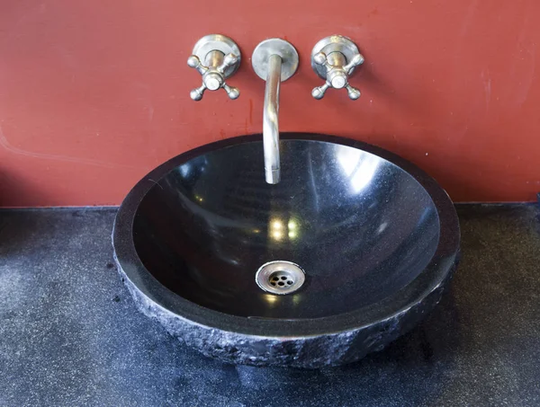 black stone sink at the red wall