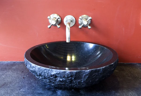 black stone sink at the red wall
