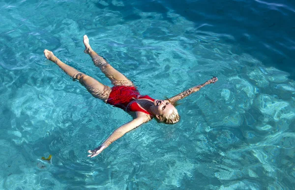 タヒチの青い海で泳ぐ赤い水着の若い女性 — ストック写真