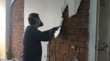 Dairede inşaat onarımı. Genç adam bir manuel inşaat instrumet kırmızı bir tuğla duvardan yüz sürü bir kaplama kaldırır