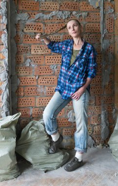 genç kadın inşaat enkaz torbaları ile bir tuğla duvar yanında duruyor ve repai düşünüyor