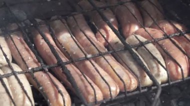 Mangalda ızgara sosisler kızartılmış ve mangal mangalında tütsülenmiş. Doğal kabuklu sosisler. Ateşin üstünde ızgara yapan lezzetli sosisler., 