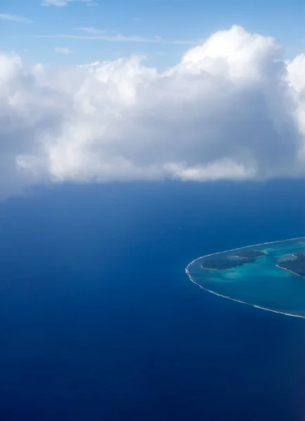 Polynesia. The atoll in ocean through clouds. Aerial view.