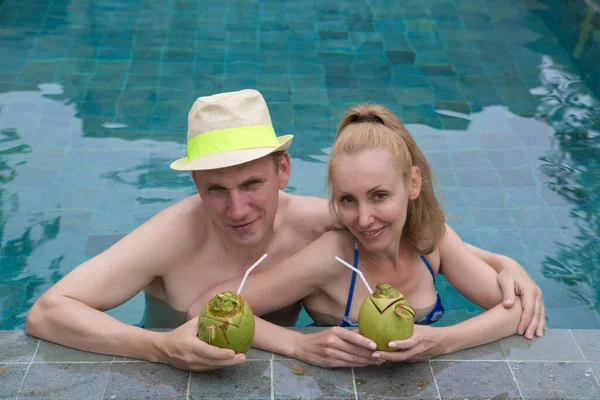 在游泳池里喝椰子鸡尾酒的快乐夫妻 — 图库照片