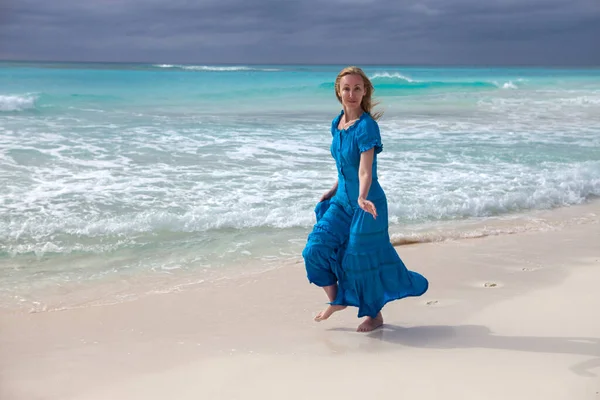 一名身穿蓝色长裙的女子在古巴开波拉戈岛的海岸 — 图库照片