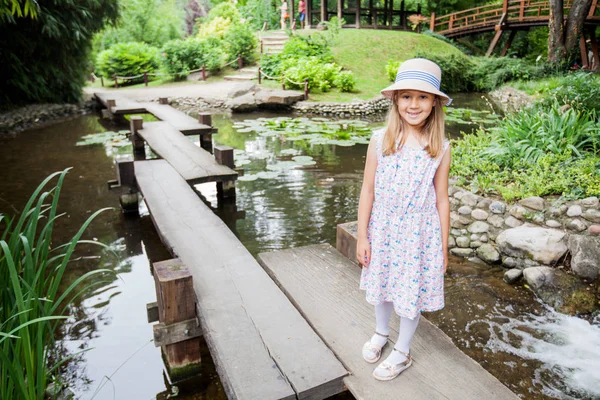 Smiling Little Girl Elegant Dress Hat Walking Wooden Bridge Pond — Stock Photo, Image