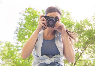 Genç kadın amatör fotoğrafçı vintage fotoğraf makinesi alarak fotoğraf Park